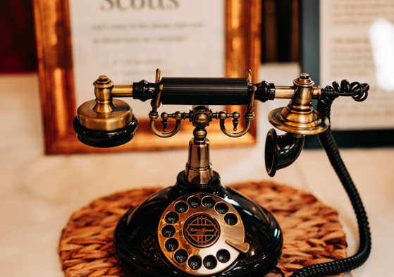 The photo shows a black vintage style audio guestbook phone with a rustic looking gold frame in the background. 